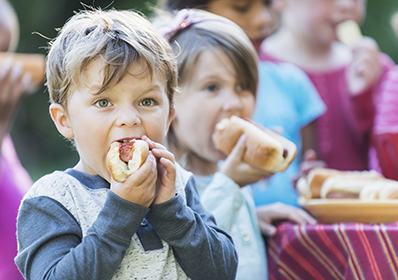 Little boy eating a hotdog at a cookout